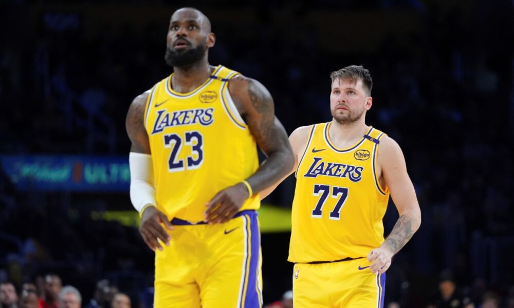 Los Angeles Lakers' LeBron James (23) and Luka Doncic (77) watch action during the second half of an NBA basketball game against the New Orleans Pelicans Tuesday, March 4, 2025, in Los Angeles. (AP Photo/Jae C. Hong)