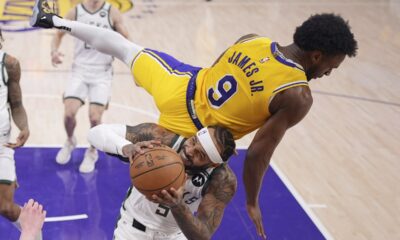 Los Angeles Lakers guard Bronny James, top, falls over Milwaukee Bucks guard Gary Trent Jr. as Trent Jr. tries to shoot during the first half of an NBA basketball game Thursday, March 20, 2025, in Los Angeles. (AP Photo/Mark J. Terrill)