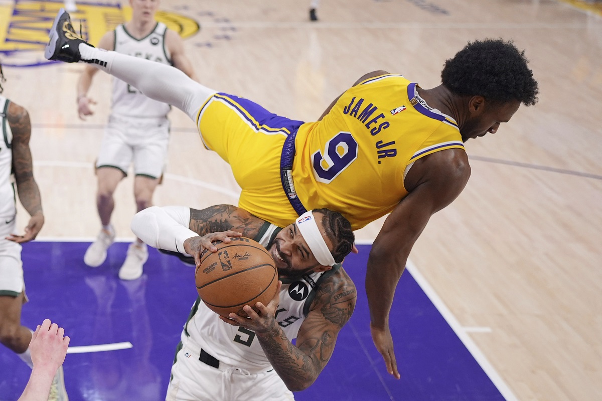 Los Angeles Lakers guard Bronny James, top, falls over Milwaukee Bucks guard Gary Trent Jr. as Trent Jr. tries to shoot during the first half of an NBA basketball game Thursday, March 20, 2025, in Los Angeles. (AP Photo/Mark J. Terrill)