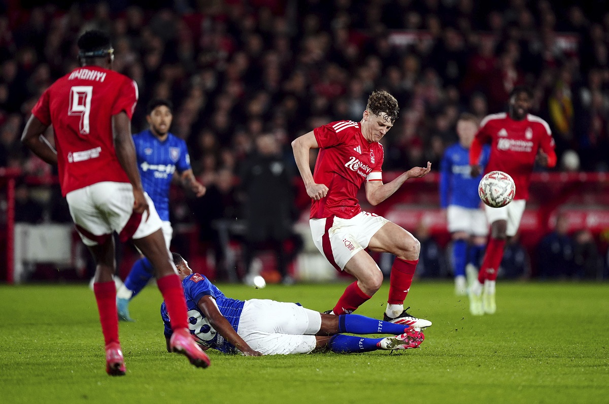 Ipswich Town's Ben Johnson, center, slides in on Nottingham Forest's Ryan Yates during the English FA Cup fifth soccer round match between Nottingham Forest and Ipswich Town at the City Ground, Nottingham, England, Monday, March 3, 2025. (Mike Egerton/PA via AP)