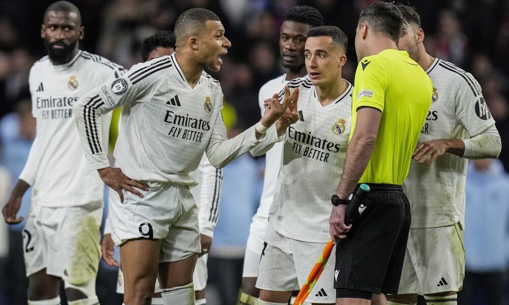 Real Madrid's Kylian Mbappe, center, talks to an assistant referee after a penalty kick by Atletico Madrid's Julian Alvarez during a shootout at the end of the Champions League round of 16, second leg, soccer match between Atletico Madrid and Real Madrid at the Metropolitano stadium in Madrid, Spain, Wednesday, March 12, 2025. (AP Photo/Bernat Armangue)
