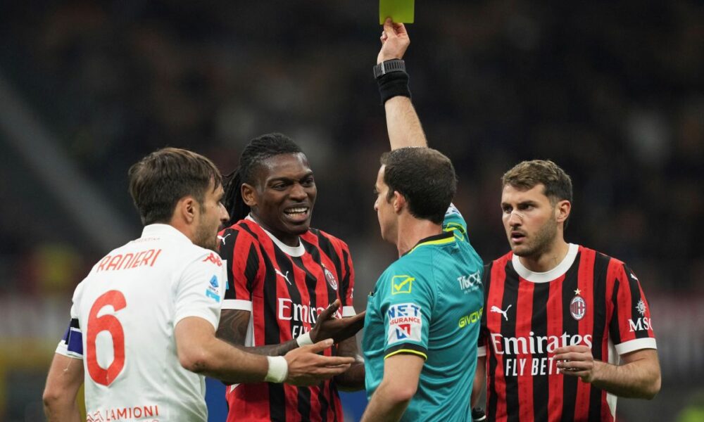 Referee Giovanni Ayroldi shows a yellow card to AC Milan's Rafael Leao during the Italian Serie A soccer match between AC Milan and Fiorentina at the San Siro Stadium in Milan, Italy, Saturday, April 5, 2025. (AP Photo/Antonio Calanni)