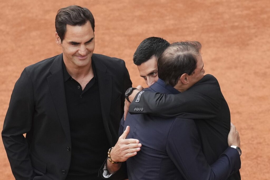 Rafa Nadal, second right, is hugged by Novak Djokovic as Roger Federer, left, look at them, during a farewell ceremony at center court Philippe-Chatrier, at the Roland-Garros stadium, in Paris, Sunday May 25, 2025. (AP Photo/Christophe Ena)