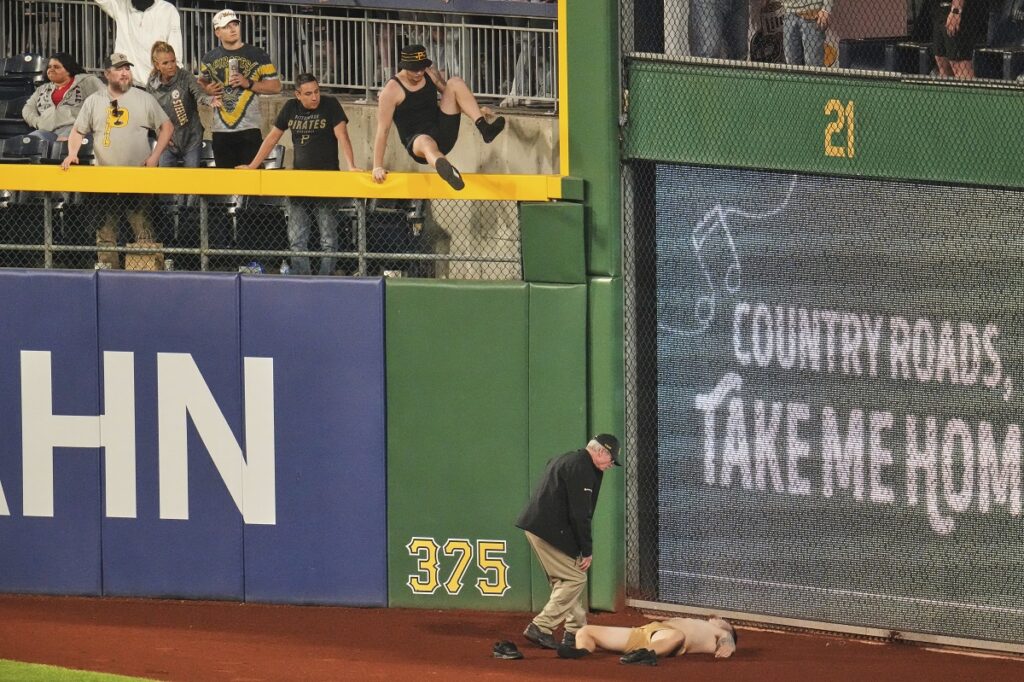A fan lies on the warning track in right field of PNC Park after falling out of the stands during the seventh inning of a baseball game between the Pittsburgh Pirates and the Chicago Cubs in Pittsburgh, Wednesday, April 30, 2025. (AP Photo/Gene J. Puskar)