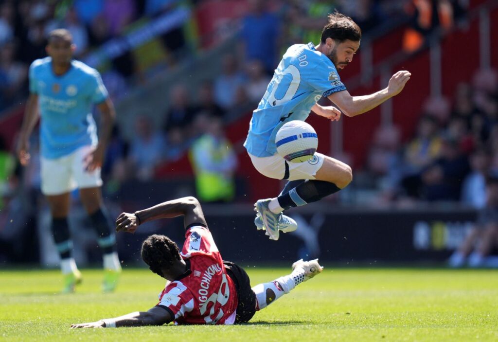 Southampton's Lesley Ugochukwu, bottom left, and Manchester City's Bernardo Silva battle for the ball during their Premier League soccer match at St Mary's Stadium, Southampton, England, Saturday May 10, 2025. (Andrew Matthews/PA via AP)