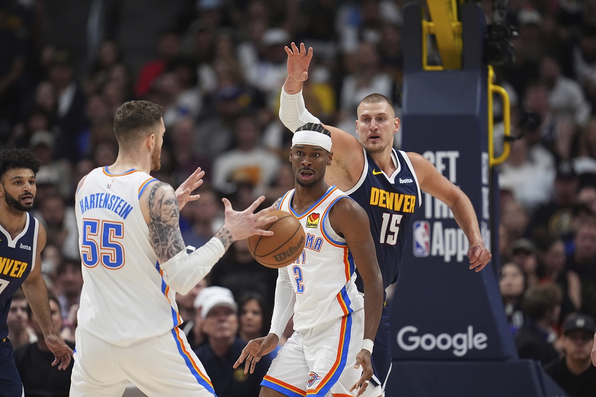 Oklahoma City Thunder center Isaiah Hartenstein (55) fields a pass from guard Shai Gilgeous-Alexander (2) as Denver Nuggets center Nikola Jokic, right, defends in the first half of Game 4 in the Western Conference semifinals of the NBA basketball playoffs Sunday, May 11, 2025, in Denver. (AP Photo/David Zalubowski)