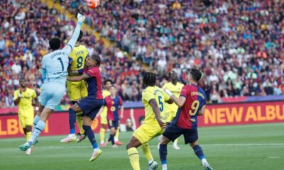 Barcelona's Raphinha, third from left, and Robert Lewandowski, right, challenge for the ball with Villarreal's goalkeeper Luiz Junior, left, Juan Foyth, second from left, and Willy Kambwala during the Spanish La Liga soccer match between Barcelona and Villarreal at Lluis Companys Olympic Stadium in Barcelona, Spain, Sunday, May 18, 2025. (AP Photo/Joan Monfort)