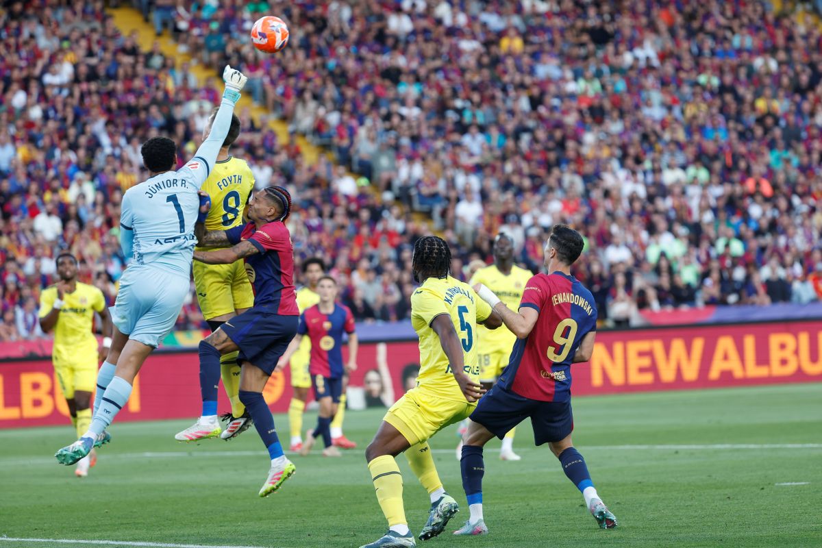 Barcelona's Raphinha, third from left, and Robert Lewandowski, right, challenge for the ball with Villarreal's goalkeeper Luiz Junior, left, Juan Foyth, second from left, and Willy Kambwala during the Spanish La Liga soccer match between Barcelona and Villarreal at Lluis Companys Olympic Stadium in Barcelona, Spain, Sunday, May 18, 2025. (AP Photo/Joan Monfort)
