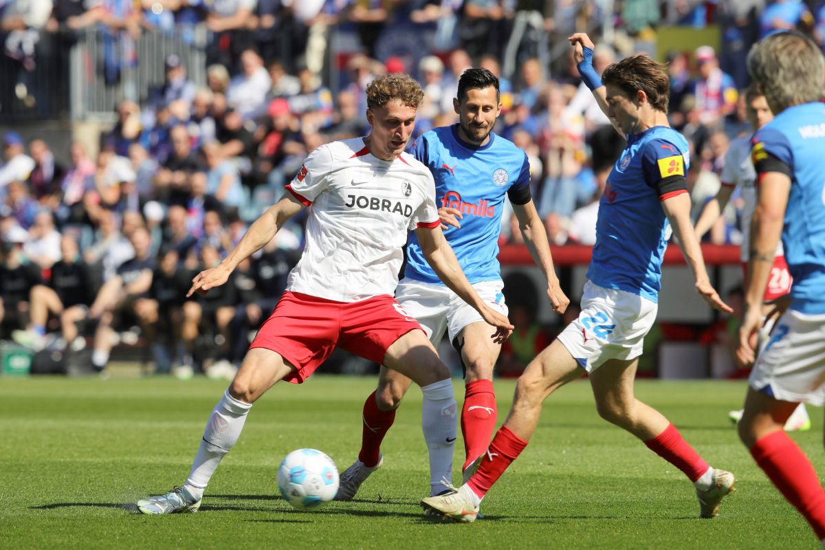 Kiel's Magnus Knudsen, right, and Kiel's Steven Skrzybski, second right, challenge for the ball during the German Bundesliga soccer match between Holstein Kiel and SC Freiburg in Kiel, Germany, Saturday, May 10, 2025. (Claus Bergmann/dpa via AP)