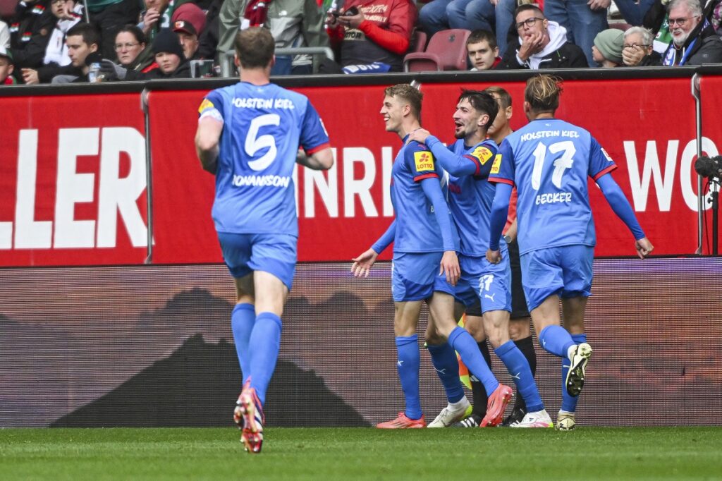 Kiel's Ivan Nekic, second left, celebrates with his teammates after scoring against Augsburg during the German Bundesliga soccer match between FC Augsburg and Holstein Kiel at the WWK-Arena in Augsburg, Germany, Sunday, May 4, 2025. (Armin Weigel/dpa via AP)