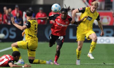 Dortmund's Daniel Svensson, right, and Leverkusen's Jeremie Frimpong, second right, challenge for the ball during the German Bundesliga soccer match between Bayer 04 Leverkusen and Borussia Dortmund in Leverkusen, Germany, Sunday, May 11, 2025. (Rolf Vennenbernd/dpa via AP)