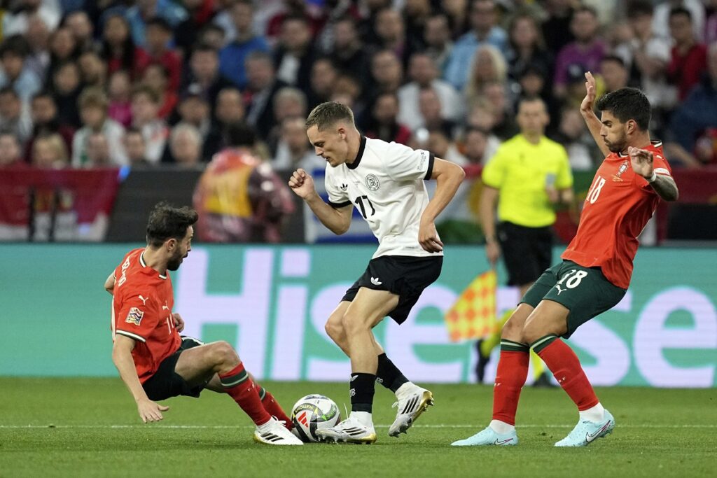 Portugal's Bernardo Silva, left, and Ruben Neves vie for the ball with Germany's Florian Wirtz during the Nations League semifinal soccer match between Portugal and Germany at the Munich Football Arena, in Munich, Germany, Wednesday, June 4, 2025. (AP Photo/Martin Meissner)