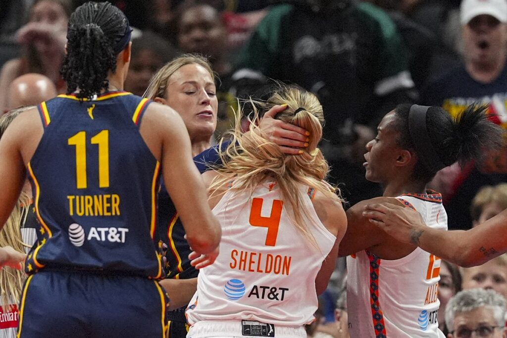 Indiana Fever guard Sophie Cunningham (8) and Connecticut Sun guard Jacy Sheldon (4) scuffle in the second half of a WNBA basketball game in Indianapolis, Tuesday, June 17, 2025. (AP Photo/Michael Conroy)