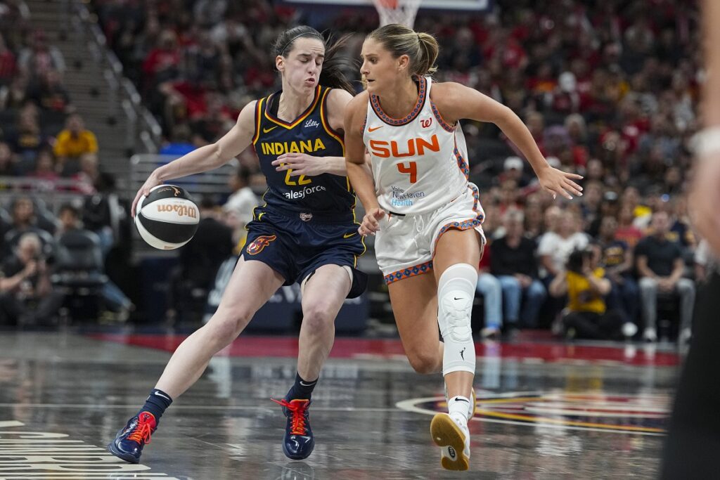 Indiana Fever guard Caitlin Clark (22) drives on Connecticut Sun guard Jacy Sheldon (4) in the second half of a WNBA basketball game in Indianapolis, Tuesday, June 17, 2025. (AP Photo/Michael Conroy)
