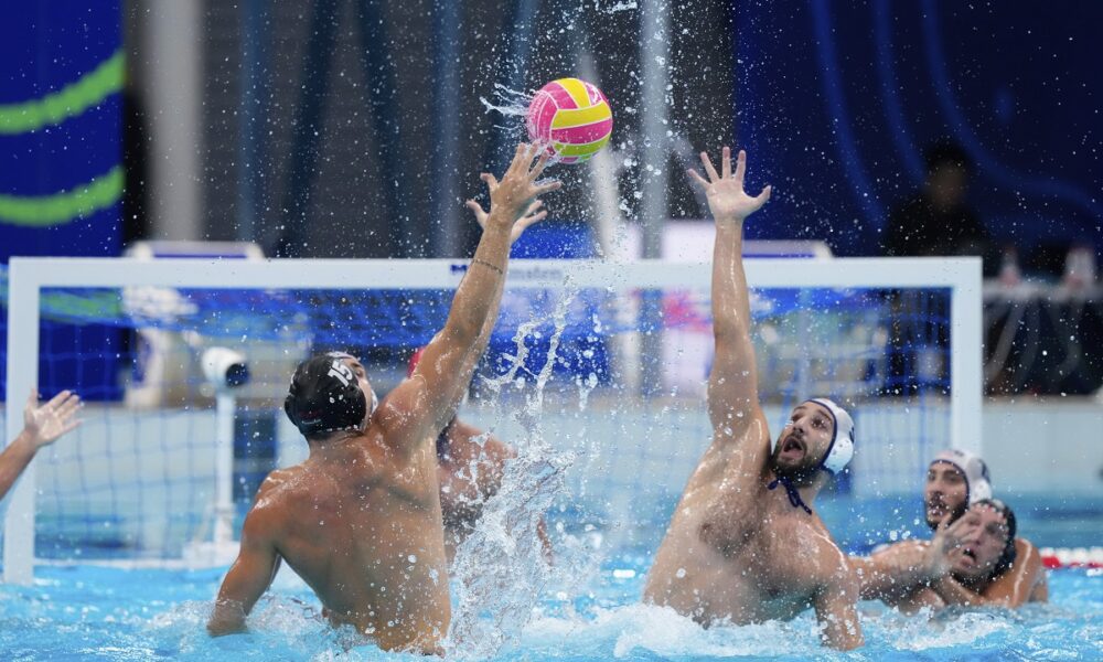 Hungary's Zsombor Vismeg, left, attempts to score against Serbia's Milos Cuk during a men's water polo semifinal match between Serbia and Hungary at the World Aquatics Championships in Singapore, Tuesday, July 22, 2025. (AP Photo/Vincent Thian)
