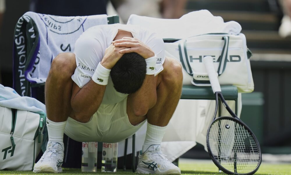 Novak Djokovic of Serbia stretches during a change of ends break as he plays Daniel Evans of Britain during their second round men's singles match at the Wimbledon Tennis Championships in London, Thursday, July 3, 2025. (AP Photo/Alastair Grant)