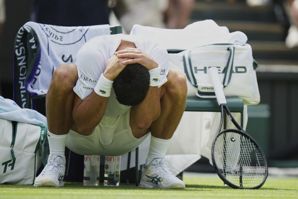 Novak Djokovic of Serbia stretches during a change of ends break as he plays Daniel Evans of Britain during their second round men's singles match at the Wimbledon Tennis Championships in London, Thursday, July 3, 2025. (AP Photo/Alastair Grant)