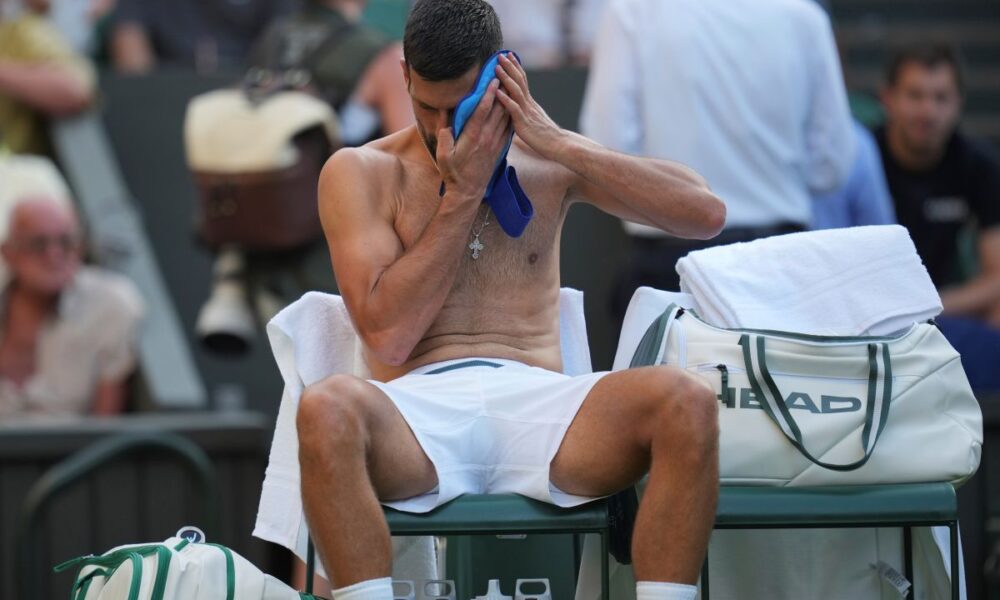 Novak Djokovic of Serbia wipes his face during a break as he plays Alexandre Muller of France during their first round men's singles match at the Wimbledon Tennis Championships in London, Tuesday, July 1, 2025. (AP Photo/Kin Cheung)
