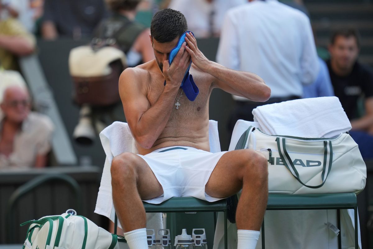 Novak Djokovic of Serbia wipes his face during a break as he plays Alexandre Muller of France during their first round men's singles match at the Wimbledon Tennis Championships in London, Tuesday, July 1, 2025. (AP Photo/Kin Cheung)