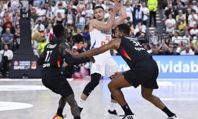 Germanys' Dennis Schröder, left,and Johannes Thiemann, right double team Serbia's Aleksa Avramovic during the final of the Supercup basketball tournament, Saturday, Aug. 16, 2025, in Munich, Germany. (Sven Hoppe/dpa via AP)