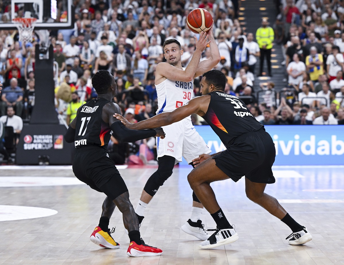 Germanys' Dennis Schröder, left,and Johannes Thiemann, right double team Serbia's Aleksa Avramovic during the final of the Supercup basketball tournament, Saturday, Aug. 16, 2025, in Munich, Germany. (Sven Hoppe/dpa via AP)